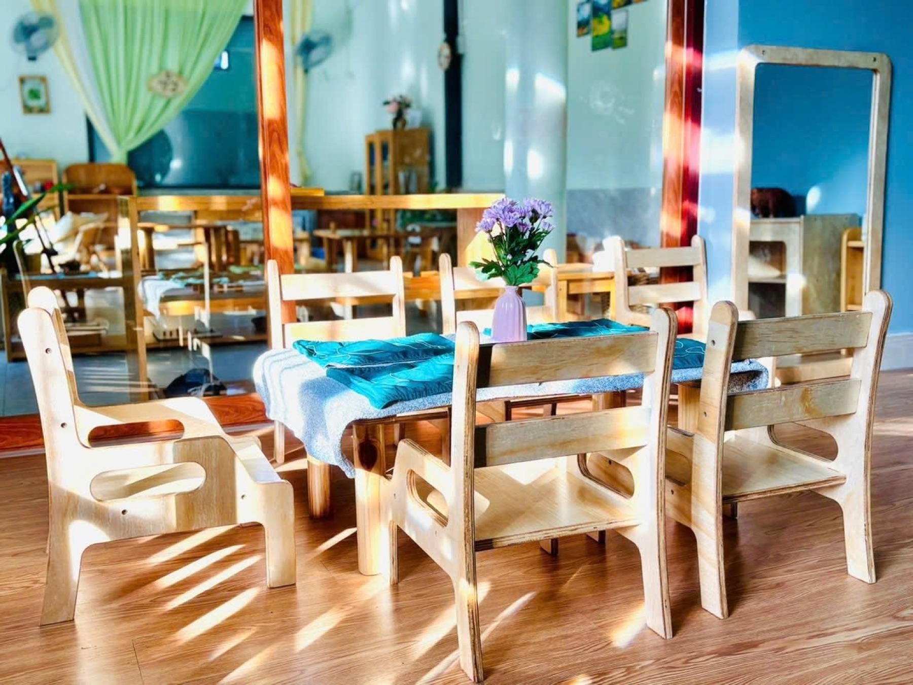 Không gian lớp Montessori với bàn ghế gỗ thấp và ánh sáng tự nhiên