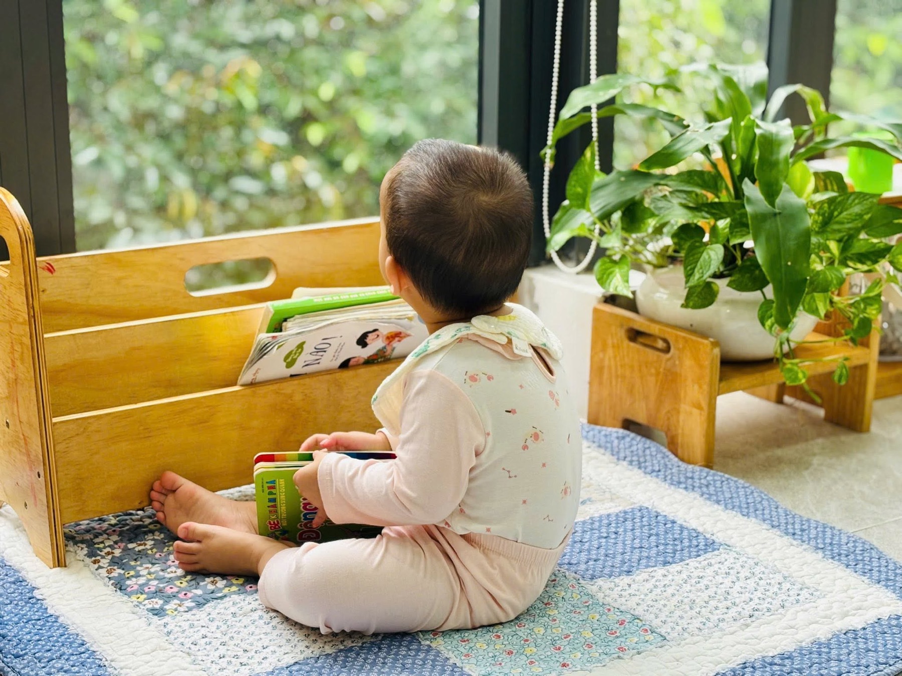 Trẻ nhỏ ngồi xem sách tại kệ sách thấp